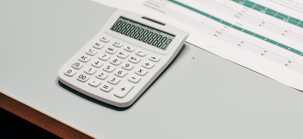 Close-up of a white calculator next to a financial spreadsheet on a desk.
